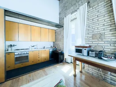 a kitchen with wooden cabinets and a brick wall at The Loft Boutique Apartment Vatican Museum in Rome