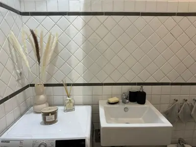 a white sink in a white tiled bathroom at JULIX - Roma Quadraro Apartment in Rome