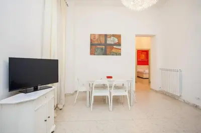 a white living room with a tv and a table and chairs at Large Apartment near Coliseum in Rome