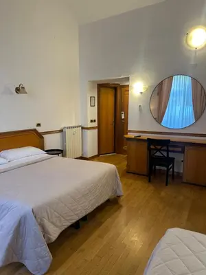 a bedroom with two beds and a desk with a mirror at Green Hotel in Rome