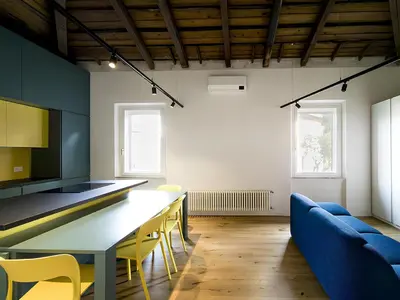 a kitchen with a table and yellow chairs in a room at La Garbatella dei Cesaroni in Rome
