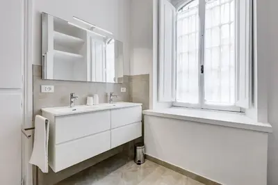 a white bathroom with a sink and a window at FaMa - Mecenate 3BR & 2BA in Rome
