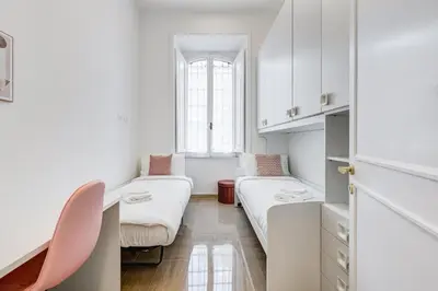 a small room with two beds and a chair at FaMa - Mecenate 3BR & 2BA in Rome