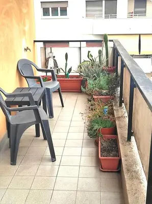 a patio with two chairs and potted plants on a balcony at Dolce Roma House - Parco Appia Antica , Netflix, Prime e Metro sotto casa in Rome
