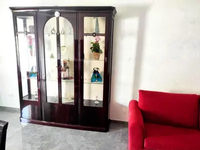 a wooden cabinet with glass doors and a red couch at Dolce Roma House - Parco Appia Antica , Netflix, Prime e Metro sotto casa in Rome