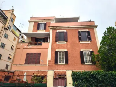a tall brick building with black shuttered windows at Domus Oleandri - WelcomeToRhome in Rome