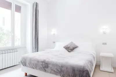 a white bedroom with a bed and a window at Vatican Grand Suite in Rome