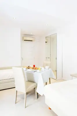 a white dining room with a table and two beds at Vatican Grand Suite in Rome