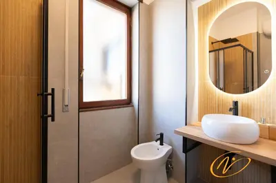 a bathroom with a toilet and a sink and a mirror at Nuccia Luxury Apartment and Suites - Terrace, bright glass lounge, 200mt to Metro-5min to Vatican, A-C in Rome