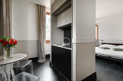 a bedroom with a bed and a table and a kitchen at Unica Suites Rome in Rome