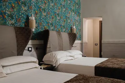 a hotel room with two beds and a floral wallpaper at Unica Suites Rome in Rome