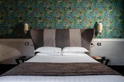 a bedroom with a large bed with a floral wallpaper at Unica Suites Rome in Rome