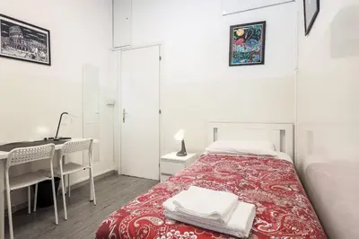 a white bedroom with a red bed and a window at San Giovanni rooms in Rome