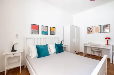 a white bed with blue pillows in a bedroom at NOSTROMONDO-Playful & Modern Apartment in the heart of Pigneto in Rome