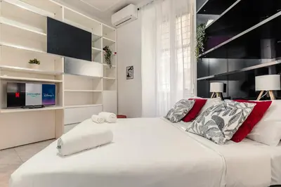 a bedroom with a large white bed and a tv at San Pietro Apartment Vatican 5 min Walk in Rome