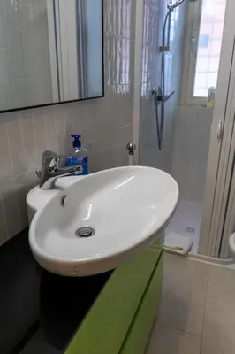 a white sink in a bathroom with a shower at San Pietro Apartment Vatican 5 min Walk in Rome