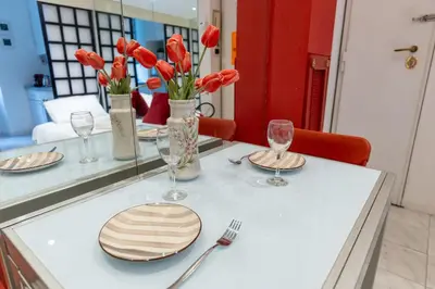 a table with plates and vases with red tulips at San Pietro Apartment Vatican 5 min Walk in Rome