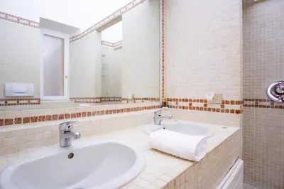 a bathroom with two sinks and two mirrors at Elegantis Ten windows on Trastevere in Rome