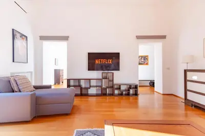 a living room with a couch and a television on a wall at Elegantis Ten windows on Trastevere in Rome