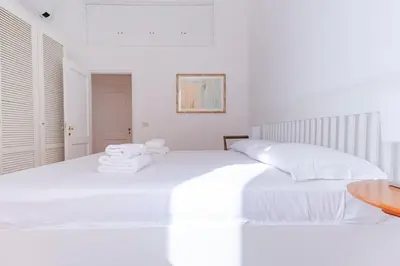 a white bedroom with a white bed with towels on it at Elegantis Ten windows on Trastevere in Rome