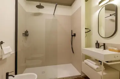 a bathroom with a shower and a sink and a mirror at Urban Garden Suites in Rome