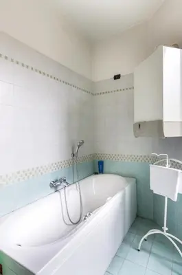 a white bath tub in a white tiled bathroom at St John Home in Rome