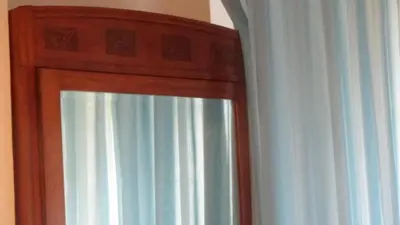 a mirror with a wooden frame next to a curtain at Bed and Breakfast Adduci's House in Rome