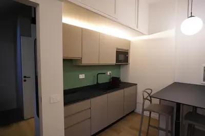 a kitchen with white cabinets and a black counter top at Renewed Historic Flat in Rome in Rome