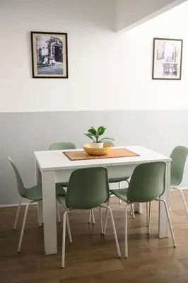 a white dining room with a white table and green chairs at Lovely apartment in the City Centre in Rome