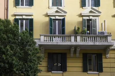 a yellow building with a balcony and green shutters at Roma San Peter Suite in Rome