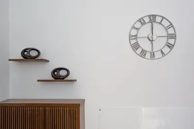 a clock on a white wall with two shelves at Roma San Peter Suite in Rome