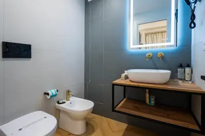 a bathroom with a sink and a toilet and a mirror at Barberini Design Suites in Rome