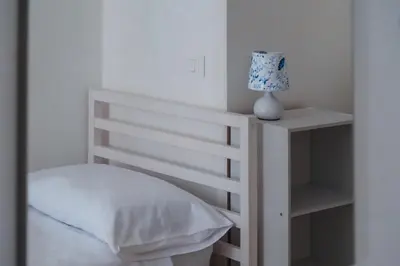 a bedroom with a white bed with a lamp on a shelf at VG Apartment - Re di Roma in Rome
