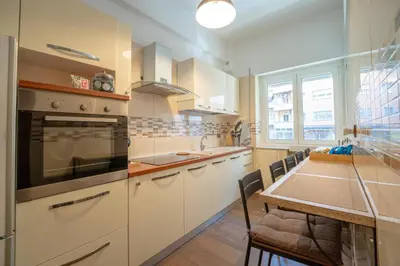 a kitchen with white cabinets and a table with a dining room at Les Maisons De Thomas Vaticano in Rome