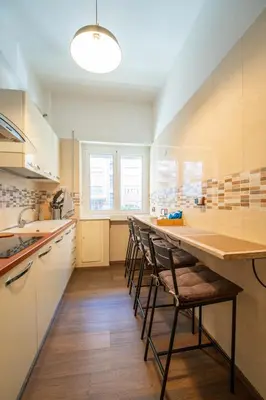 a kitchen with a long counter with chairs in it at Les Maisons De Thomas Vaticano in Rome
