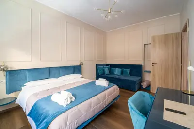 a bedroom with a blue bed and a couch at Les Maisons De Thomas Vaticano in Rome