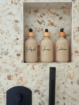 three bottles of detergent on a shelf in a bathroom at Santa Maria Apartment Rome in Rome