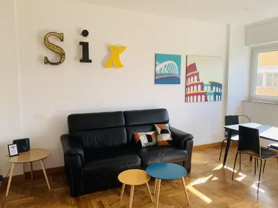 a living room with a black leather couch and tables at Apartment SIX Rome Flaminio - Villaggio Olimpico in Rome