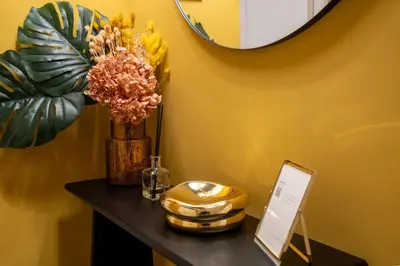 a table with a mirror and a vase with flowers on it at Maison Luxury Plaza in Rome