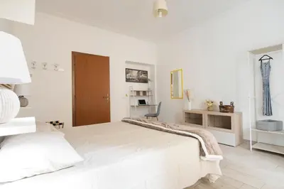 a white bedroom with a large bed and a chair at Holiday Season in Rome