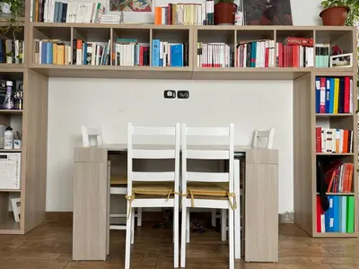 a table and chairs in a room with bookshelves at Cozy house with terrace in Rome