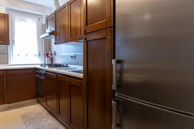 a kitchen with wooden cabinets and a stainless steel refrigerator at Apartment Casa Girina Boutique in Rome
