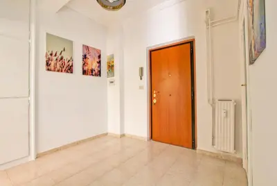 a hallway with a wooden door and paintings on the walls at White Boutique Apartment in Rome