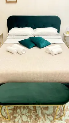 a bed with a green headboard and pillows on it at Pantheon Luxury Jacuzzi Apartment in Rome