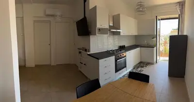a kitchen with white cabinets and a wooden table in it at Home in Roma in Rome