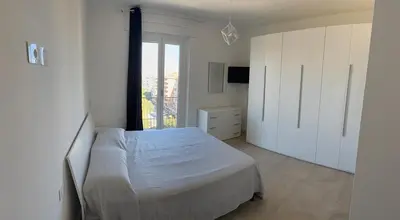 a white bedroom with a bed and a window at Home in Roma in Rome