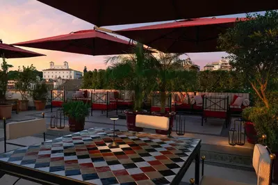 a checkered table and chairs on a patio with umbrellas at Hotel d’Inghilterra Roma – Starhotels Collezione in Rome