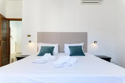 a bed with white sheets and green pillows at NEW Diana's place with terrace San Pietro Station in Rome