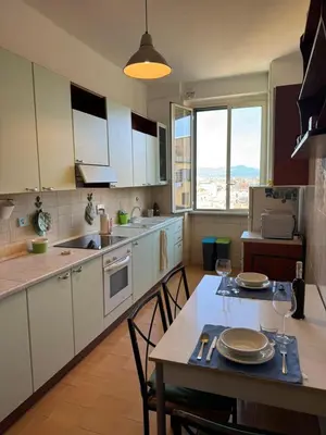 a kitchen with white cabinets and a table with chairs at House - Furio Camillo - Too in Rome