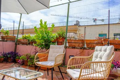 two chairs and a table on a balcony with plants at Elegantis Monti Penthouse With Private Terrace and Colosseum View in Rome